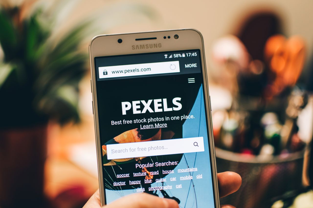 services-04 A close-up view of a smartphone displaying the Pexels website screen for stock photo searches.