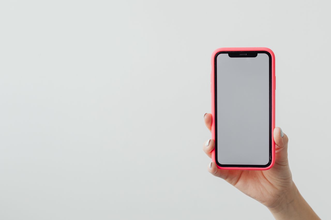 services-02 A hand holding a smartphone with a red case against a clean white background, ideal for tech concepts.